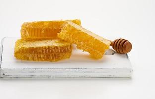 wax honeycomb with honey on a white board and a wooden spoon photo