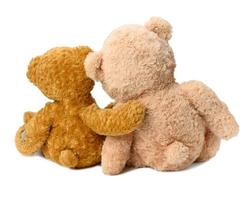 two teddy bears sit with their backs on a white isolated background. Love and friendship photo