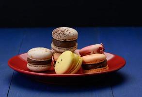 macarons de almendras al horno en un plato de cerámica roja, fondo azul foto