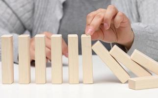 hand stops the fall of wooden blocks on a white background. Concept of a strong and courageous personality capable of withstanding unequal difficulties. Strong business photo