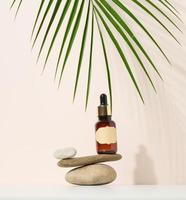 una botella de vidrio marrón con una pipeta y una etiqueta marrón se encuentra sobre una piedra. contenedor para cosméticos, suero y aceite foto