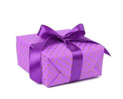 rectangular box wrapped in purple polka dot paper and tied with a silk ribbon on a white background photo