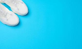 White textile sneakers on a blue background, top view photo