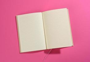 open notebook with blank white sheets on pink background photo
