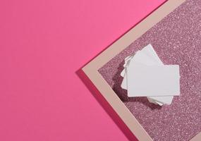 la tarjeta de visita rectangular en blanco se encuentra sobre un moderno fondo rosa hojas de papel con una sombra