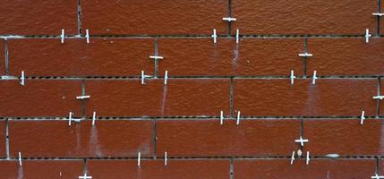 azulejos marrones en proceso de colocación. cruces auxiliares de plástico blanco en las ranuras foto