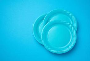 Empty white paper disposable plates on a bluen background, top view. The concept of rejection of plastic, environmental conservation photo