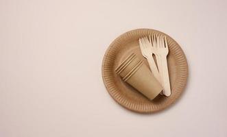 Brown paper cups and plates on a beige background. Recyclable garbage, rejection of plastic photo