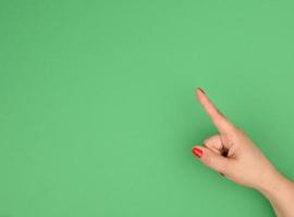 mano femenina con el dedo índice levantado sobre fondo verde foto