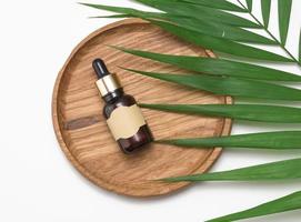 brown glass bottle with a pipette and with blank paper label on a white background. Container for cosmetics, serum and oil photo