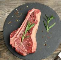 fresh piece of beef, striploin steak on a black board with spices photo