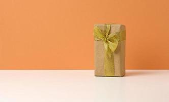 brown gift box on white table, orange background, surprise and gift photo