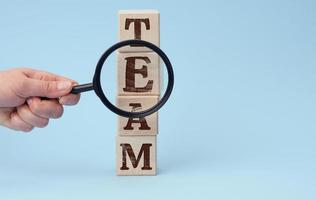 hand with a magnifying glass on a blue background. The concept of recruiting and finding talented employees photo
