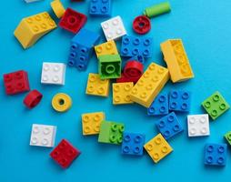 Scattered parts of a plastic children's designer, top view. Yellow blue background photo