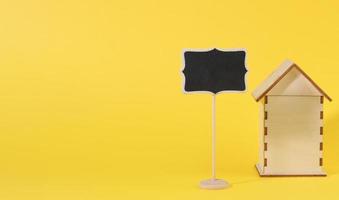 mini wooden house and chalk pointer on a yellow background. Real estate purchase concept photo