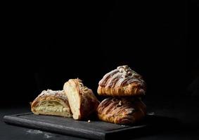 baked croissants on a black wooden board sprinkled with powdered sugar photo