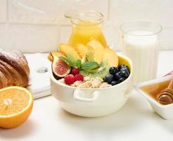 plato con avena y fruta, media naranja madura y jugo recién exprimido en un decantador de vidrio transparente, miel en un bol sobre una mesa blanca. desayuno saludable foto