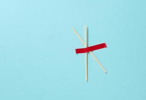 pair of wooden sticks glued with red sticky tape on a blue background, top view photo