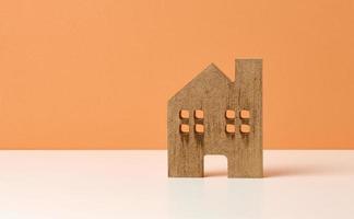 casa de madera marrón sobre un fondo naranja. concepto de alquiler, compra y venta de bienes raíces. servicios inmobiliarios, reparación y mantenimiento de edificios foto