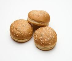 bollo de harina de trigo blanco fresco redondo horneado espolvoreado con semillas de sésamo sobre una mesa blanca. hamburguesa, hamburguesa con queso y bollo de sándwich foto