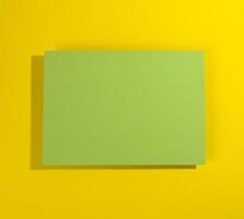 blank green sheet of paper on yellowe background with shadow photo