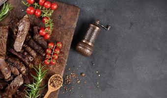 roasted piece of beef ribeye cut into pieces on a vintage brown chopping board. Delicious steak, copy space photo