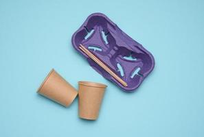 disposable brown paper cups, wood sticks and paper tray on blue background. Takeaway beverage container photo