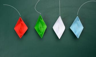 paper boats sail in different directions on a green background. concept of leadership photo