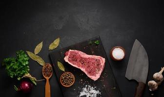 fresh raw piece of beef meat, striploin steak on a black background, top view. Marbled piece of meat New York photo