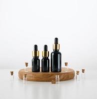 botella de vidrio marrón con una pipeta en un podio de madera y una rama de eucalipto. publicidad y promoción de productos cosméticos.