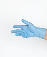 Doctor's hand in a blue medical glove holds an object on a white background. Copy space