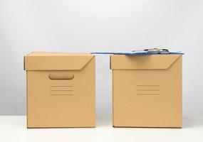 two cardboard boxes made of brown corrugated cardboard are on a white table, moving, goods delivery photo