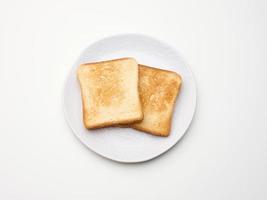 pedazos cuadrados de pan tostado hechos con harina de trigo blanco en un plato redondo. fondo de mesa blanca foto