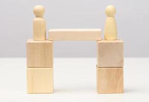 wooden figures stand on the bridge from the sides opposite each other, concept of finding a compromise, constructive dialogue, business opponents photo