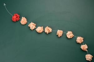 crumpled balls of paper lie in a row, red in front. The concept of a strong leader photo