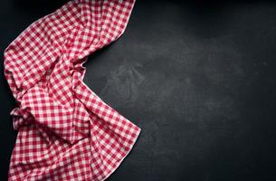 Folded red and white cotton kitchen napkin on a wooden black background, top view, copy space photo