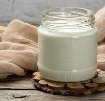 homemade yogurt in a glass transparent jar on a wooden table photo