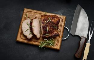 baked piece of pork meat in spices on a wooden board, cut into pieces. Eye of round roast steak photo