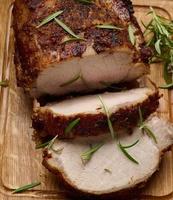 trozo de carne de cerdo al horno con especias sobre una tabla de madera, cortado en trozos. ojo de filete asado redondo foto