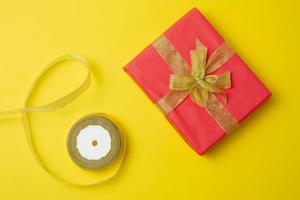 wrapped boxes in gift red paper and silk ribbon on a yellow background, top view. Congratulations and surprise photo