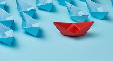 group of paper boats on a white background. concept of a strong leader in a team, manipulation of the masses, following new perspectives, collaboration and unification photo