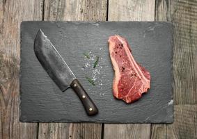 fresh raw piece of beef meat, striploin steak on a wooden background, top view. Marbled piece of meat photo