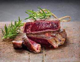 fried piece of beef ribeye, cut into pieces on a brown wooden board, rare doneness photo