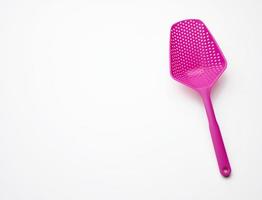 pink plastic spoon with holes for mixing salad on a white background, top view photo