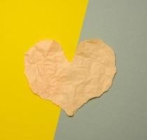 corazón hecho de papel rasgado sobre un fondo gris-amarillo foto