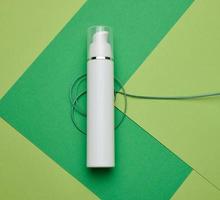 botella de plástico blanca vacía sobre un fondo verde. productos cosméticos para branding gel, crema, loción, champú