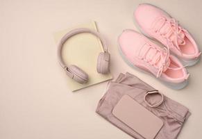 pair of pink sneakers, wireless headphones, a smartphone and a smart watch on a pink background photo