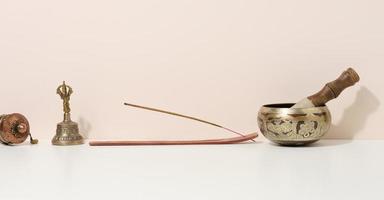 copper singing bowl and wooden clapper on a white table. Musical instrument for meditation, relaxation, various medical practices related to biorhythms, normalization of mental health photo