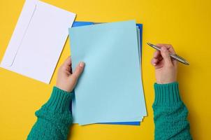 hojas blancas en blanco y dos manos femeninas, vista superior. escritura de texto, lista foto