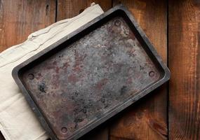 empty rectangular iron rusty baking sheet on a wooden brown table, top view photo